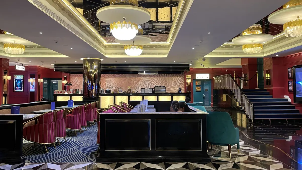 Lounge seating and bar counter inside Aurus Mall under gold chandeliers